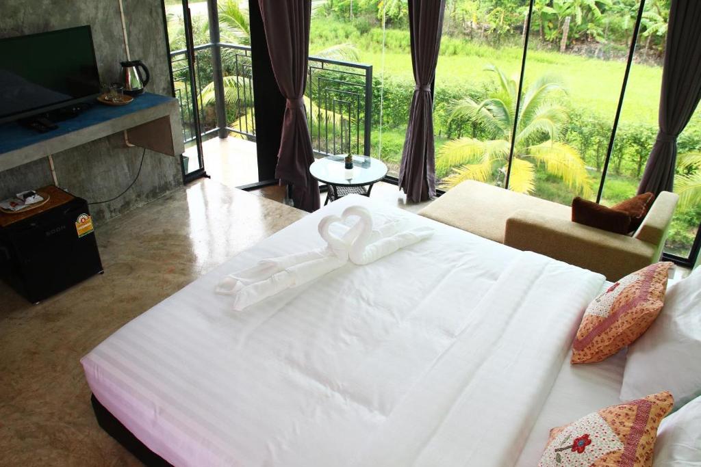 um quarto com uma cama branca com um laço em Plernsalaya resort em Salaya