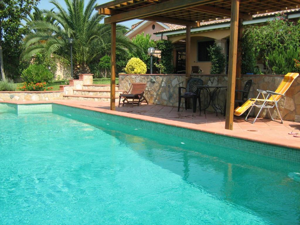 una piscina accanto a una casa con patio di B&B Sedici Pini a Pomezia