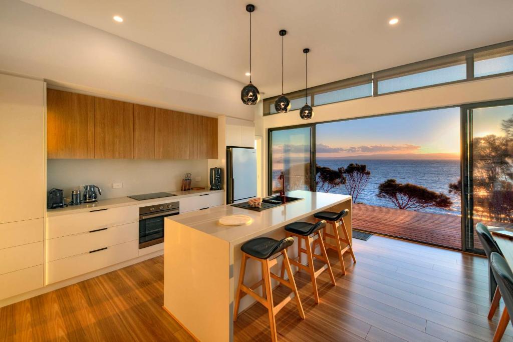 uma cozinha com uma ilha e vista para o oceano em Freycinet Coastal Retreat em Coles Bay