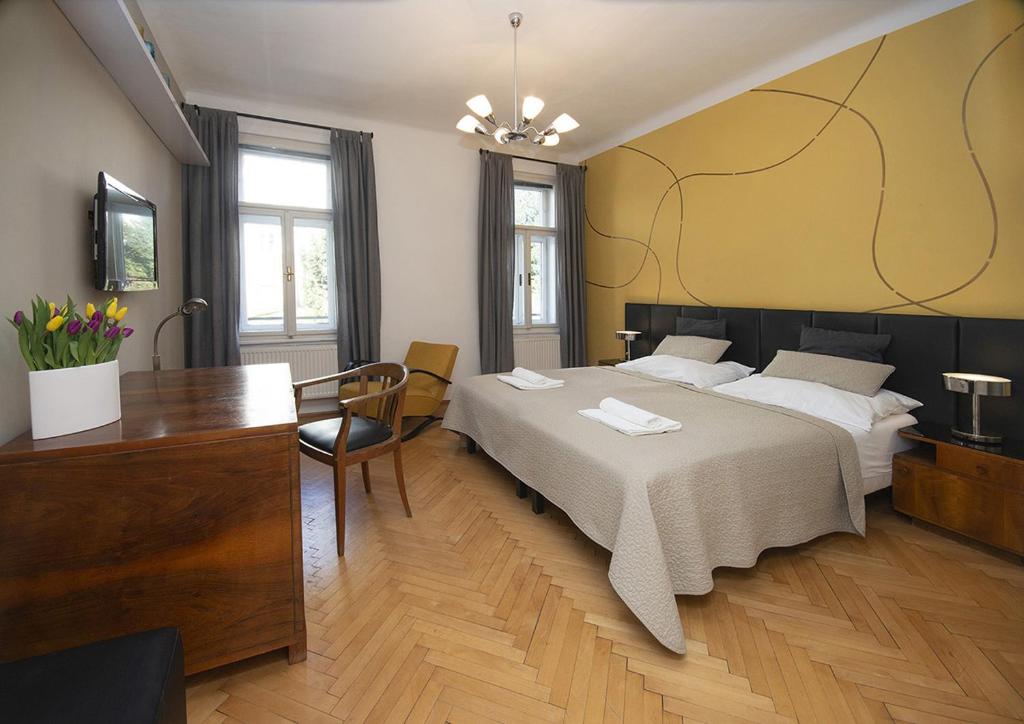 een slaapkamer met een bed, een bureau en een televisie bij Bed&Breakfast & Apartment Klafé in Brno