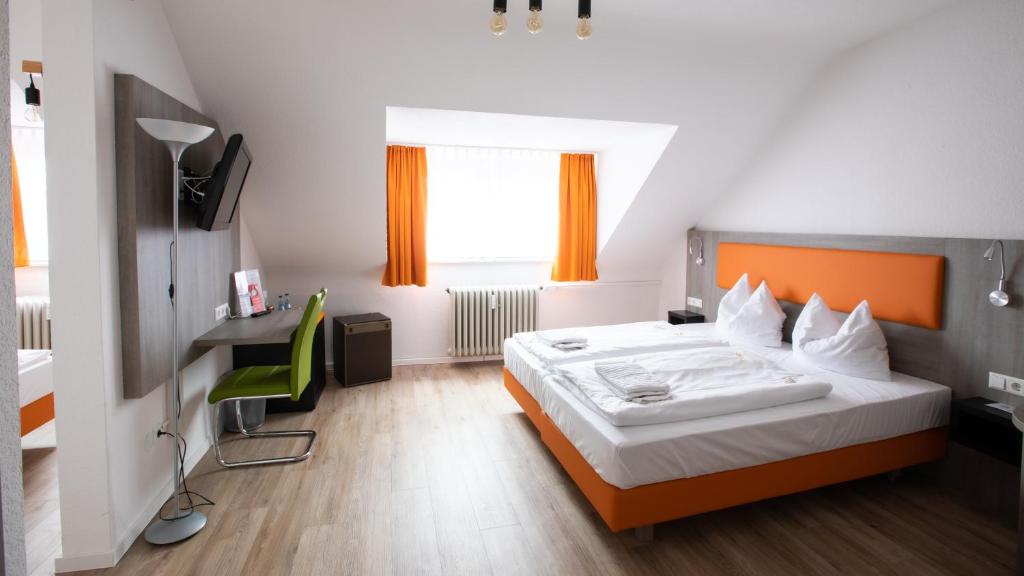 1 dormitorio con 1 cama y escritorio con silla verde en Hotel Astoria, en Karlsruhe