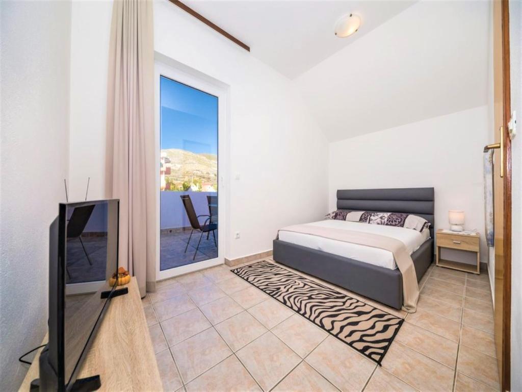 a bedroom with a bed and a tv and a balcony at Apartment Sensa in Trogir