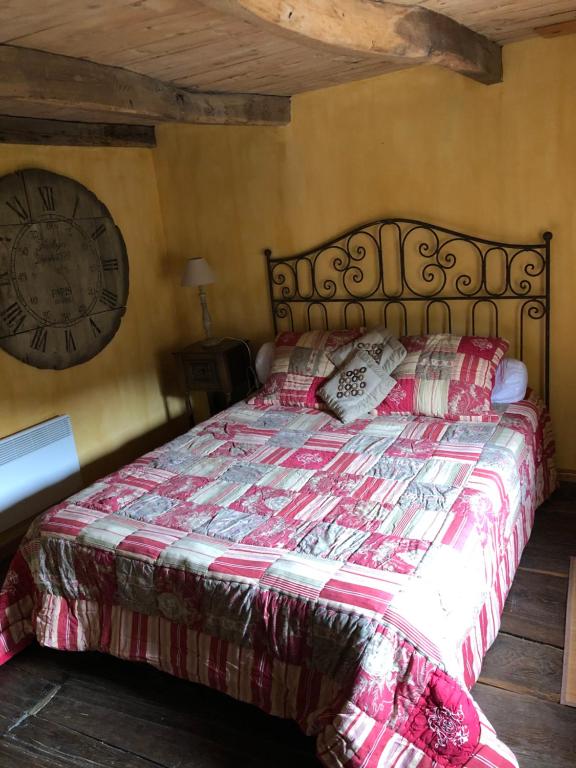 a bedroom with a bed with a clock on the wall at Le Boustrophédon in Antraigues