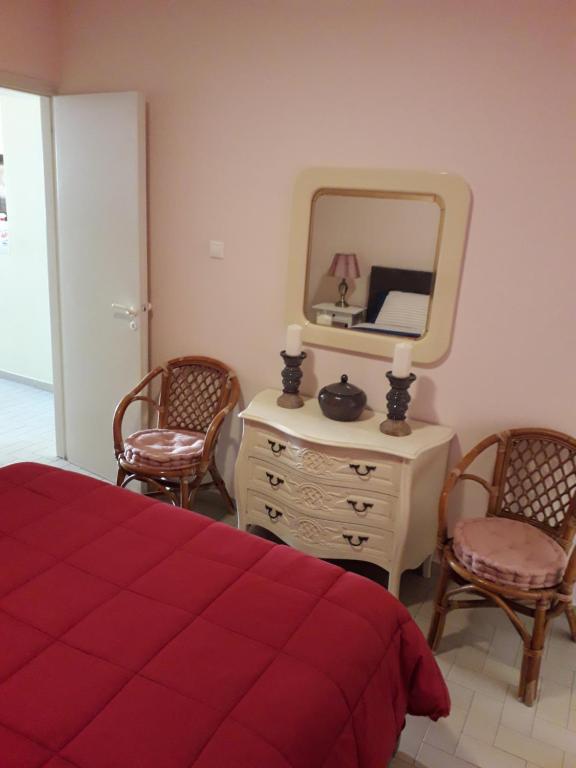 Schlafzimmer mit einem Bett, einem Spiegel und Stühlen in der Unterkunft Rafina K-Apartment in Rafina