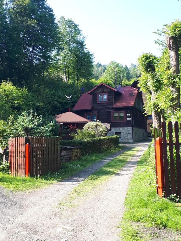 a dirt road in front of a house with a fence at Chata z bali in Sucha Beskidzka