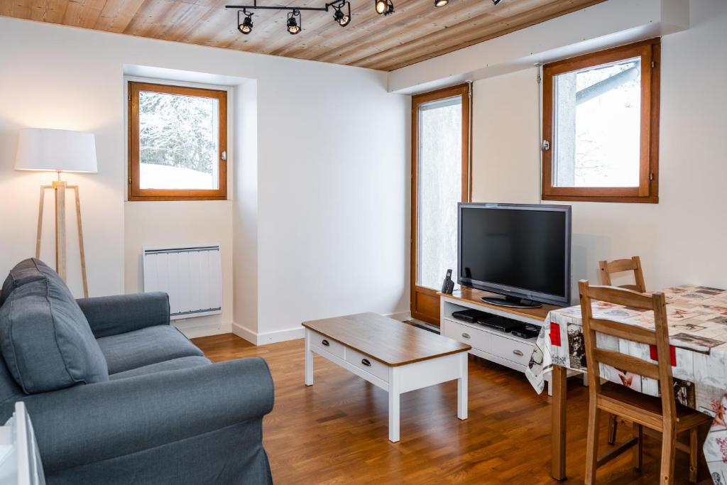 a living room with a couch and a tv at Le Refuge in Lamoura