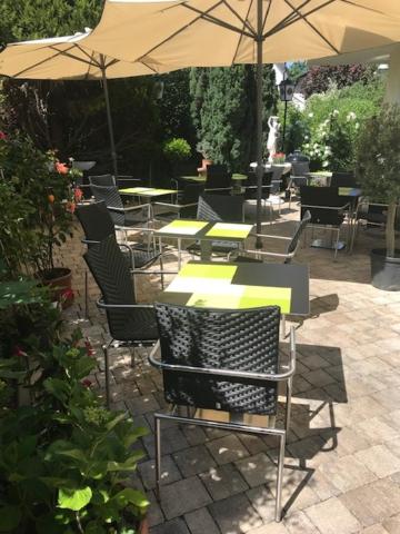 a patio with tables and chairs and an umbrella at Westend Hotel in Ludwigsburg