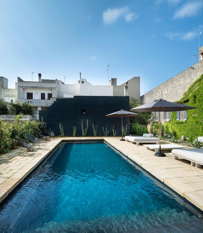 a swimming pool with chairs and umbrellas on a building at Palazzo Daniele, a Member of Design Hotels in Gagliano del Capo