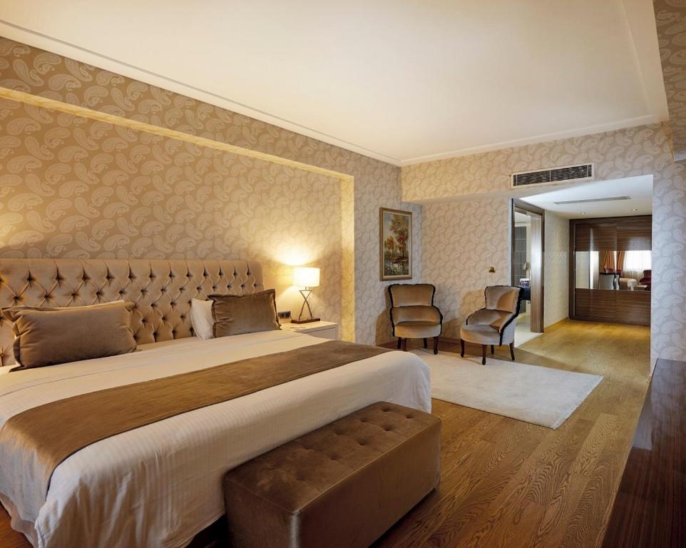 a large bedroom with a large bed and chairs at Anemon Grand Konya Otel in Konya