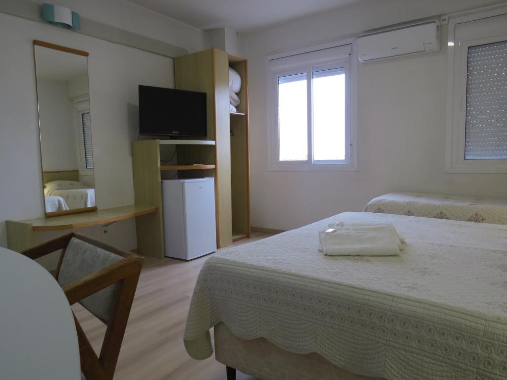 a hotel room with a bed and a tv and a room at City Hotel in Caxias do Sul