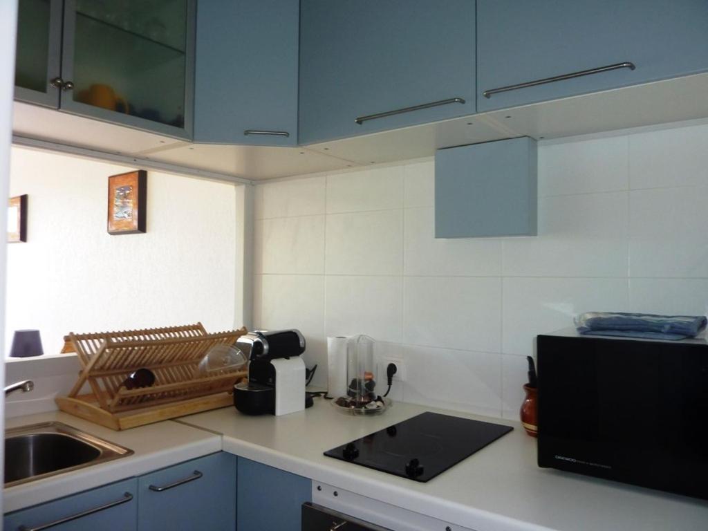 a kitchen with blue cabinets and a sink and a microwave at AS13247 - P2 Cabine climatisé avec belle vue sur la Mer in Le Grau-du-Roi