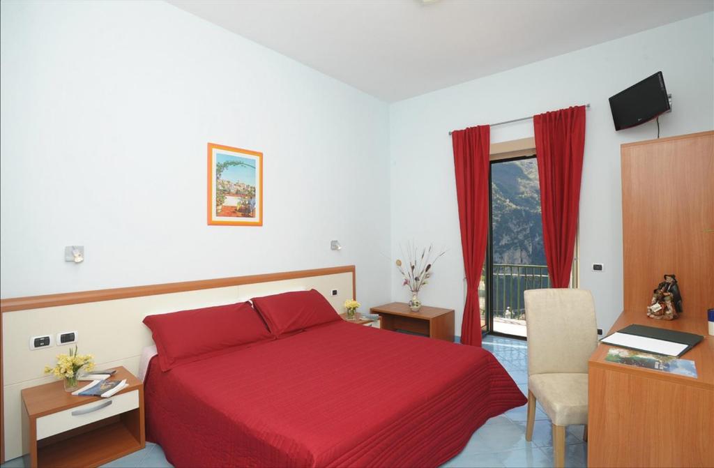 a hotel room with a red bed and a desk at Dint'a Torre Bed and Breakfast in Scala