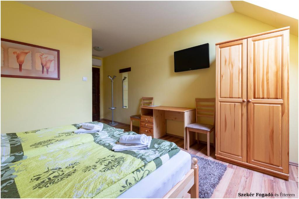 a bedroom with a bed and a desk and a television at Szekér Fogadó in Bátonyterenye