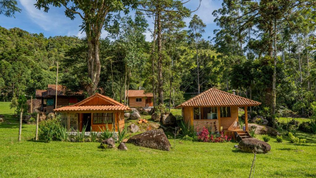 dos casitas de campo pequeñas en un campo con árboles en Chalés Das Estrelas, en Visconde De Maua