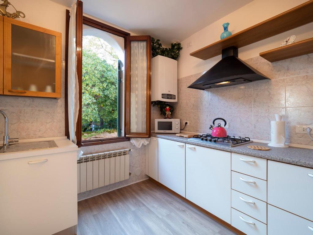 una cocina con armarios blancos y una ventana en Canal Tron, en Venecia