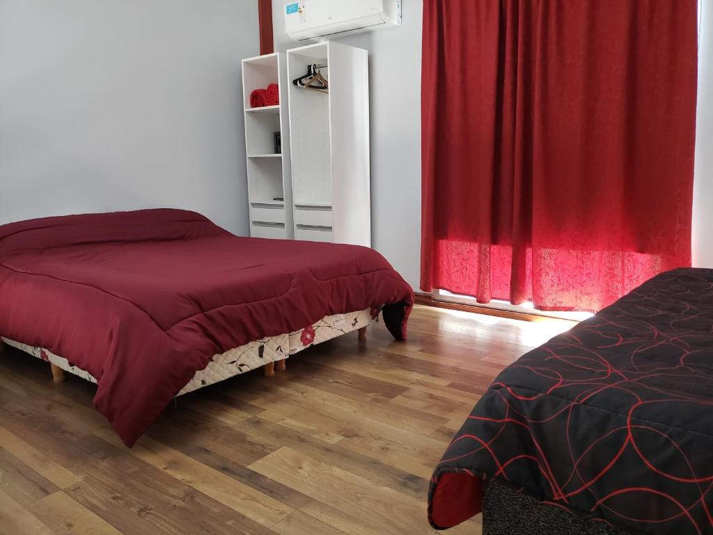 1 dormitorio con 2 camas y cortinas rojas en Lugones en Ezeiza