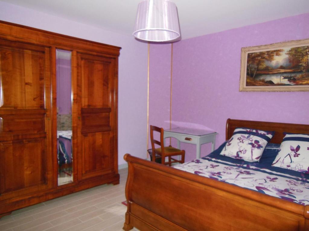 a bedroom with purple walls and a bed and a chair at LES BRUYERES in Chaptelat