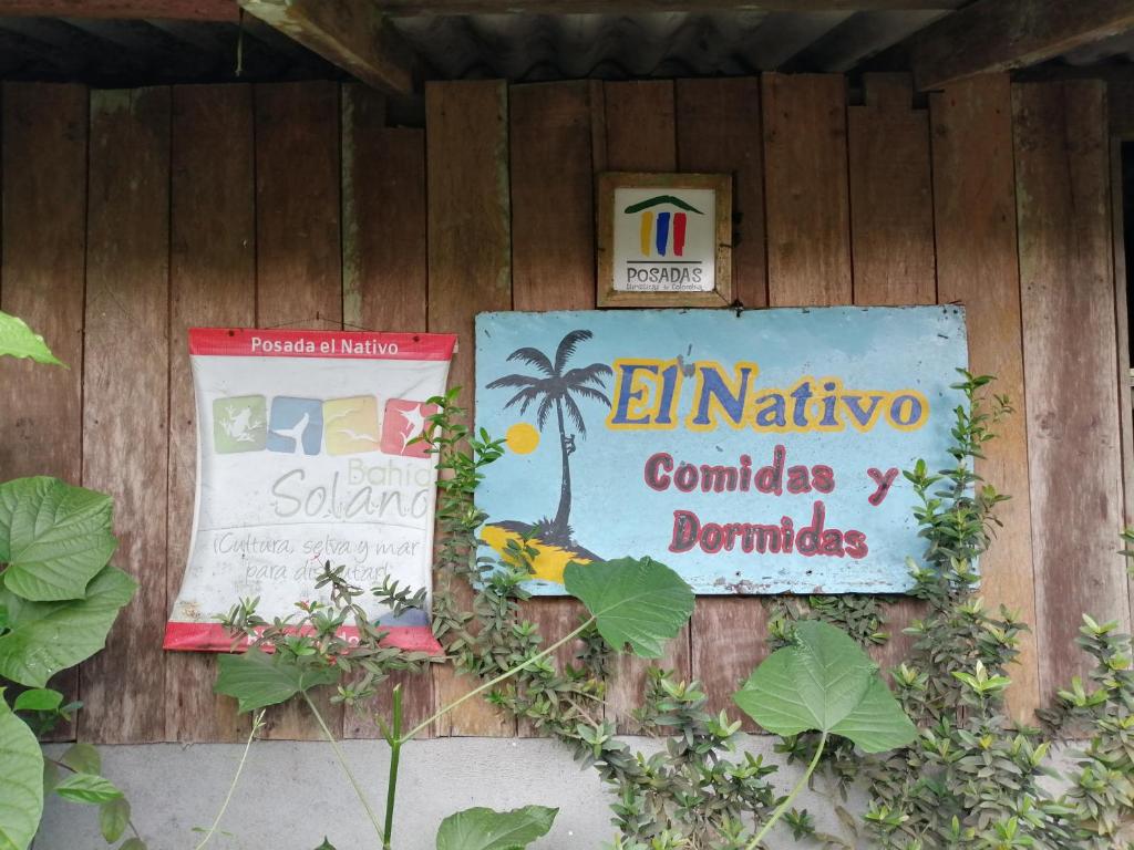 a sign on a wooden wall with plants at Posadas el Nativo in Bahía Solano