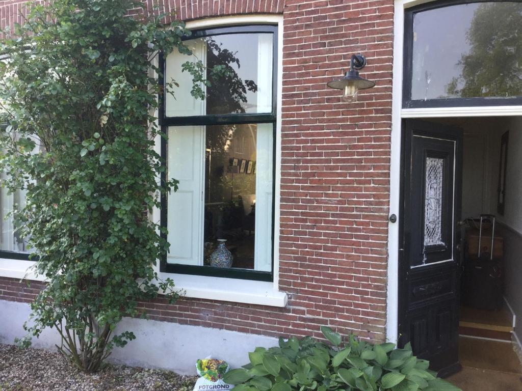 une maison en briques rouges avec une porte noire et une usine dans l'établissement Charming countryhouse near Amsterdam, à Abcoude