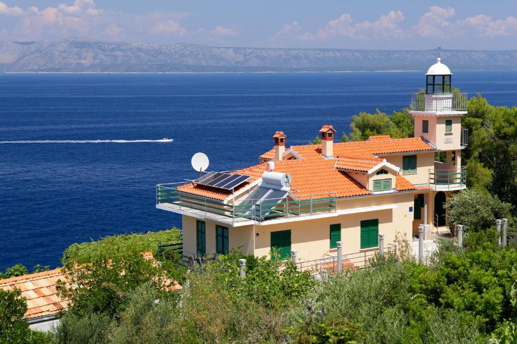 a house with a lighthouse on top of the ocean at Unique seaside villa with pool in Vela Luka