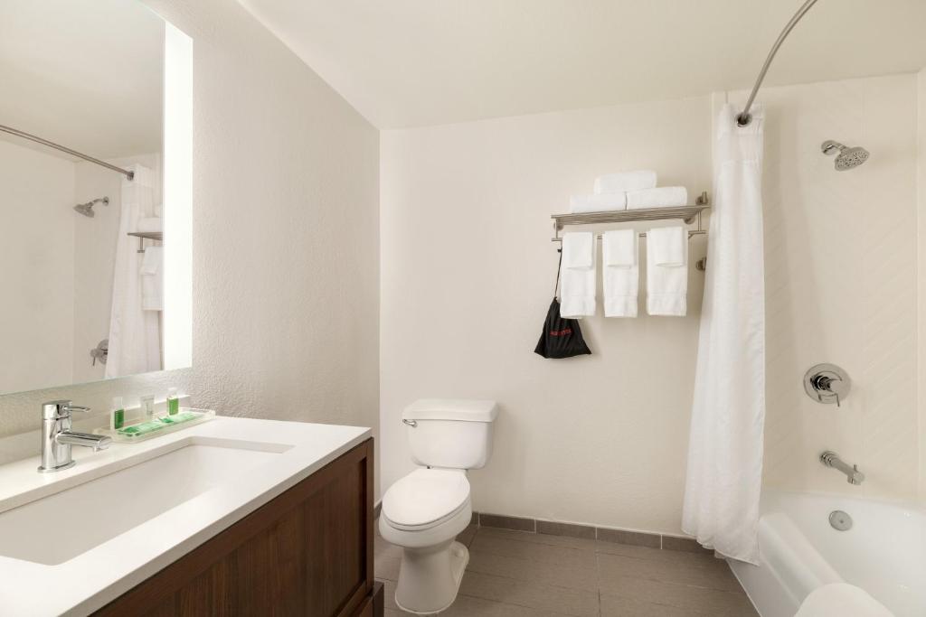 a white bathroom with a toilet and a sink at Holiday Inn Houston Intercontinental Airport by IHG in Houston