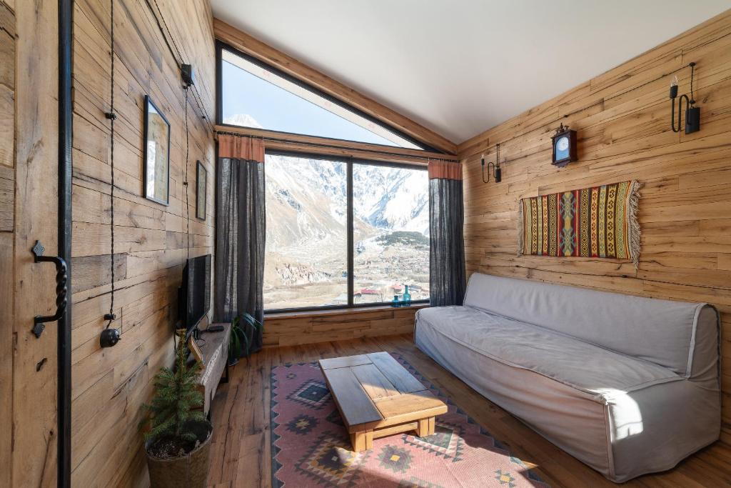 a living room with a couch and a large window at Kazbegi cabins in Stepantsminda
