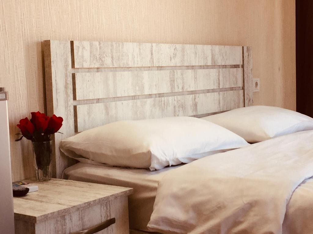 a bedroom with two beds and a vase of red roses at Hotel Tourist in Tbilisi City