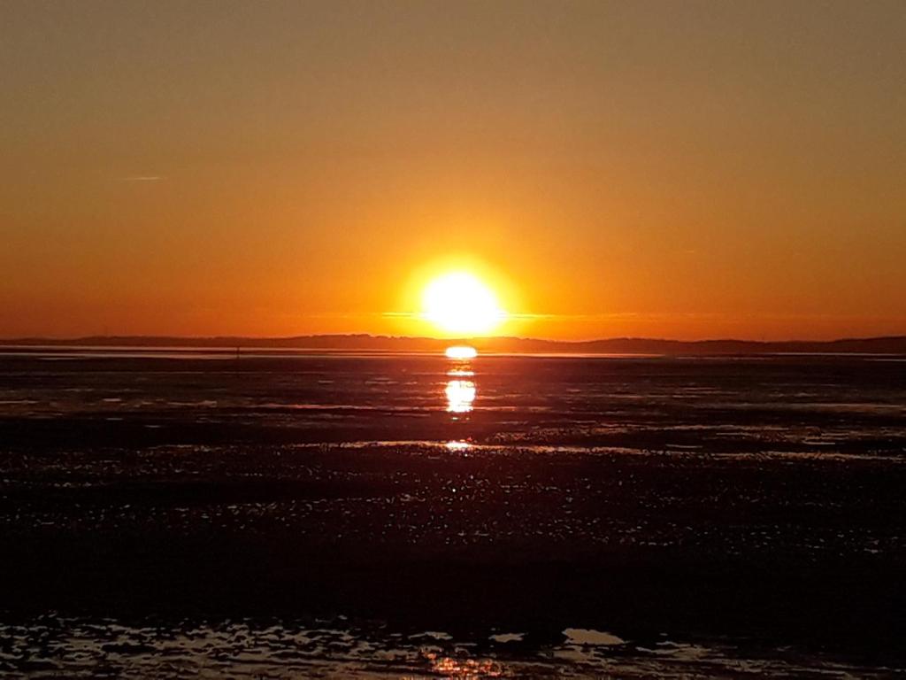 una puesta de sol sobre el océano con el sol en el cielo en lanton, en Lanton