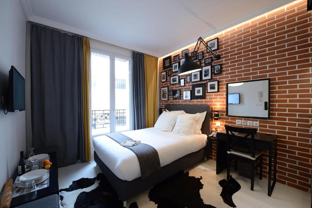 pokój hotelowy z łóżkiem i ceglaną ścianą w obiekcie Résidence Voûte w Paryżu