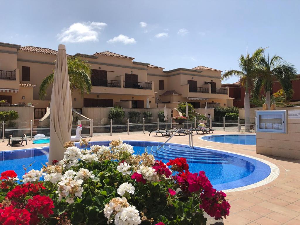 una piscina con fiori di fronte a un edificio di Villa Del Duque with private pool ad Adeje