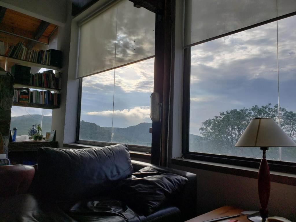 ein Wohnzimmer mit einem Sofa und zwei großen Fenstern in der Unterkunft Casa en las Sierras de Córdoba in Unquillo