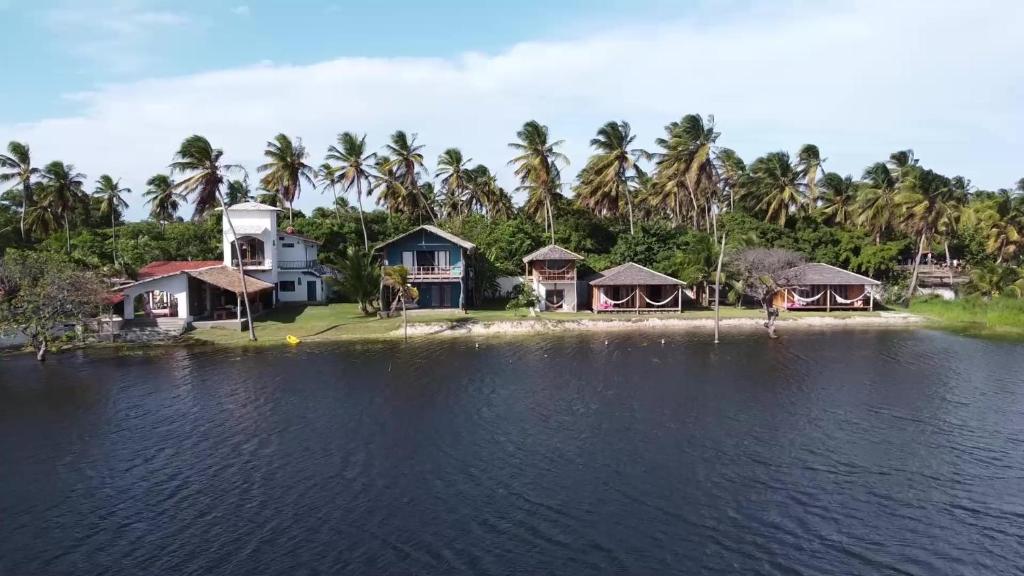 um grupo de casas numa praia com palmeiras em Casa na Lagoa em Paracuru