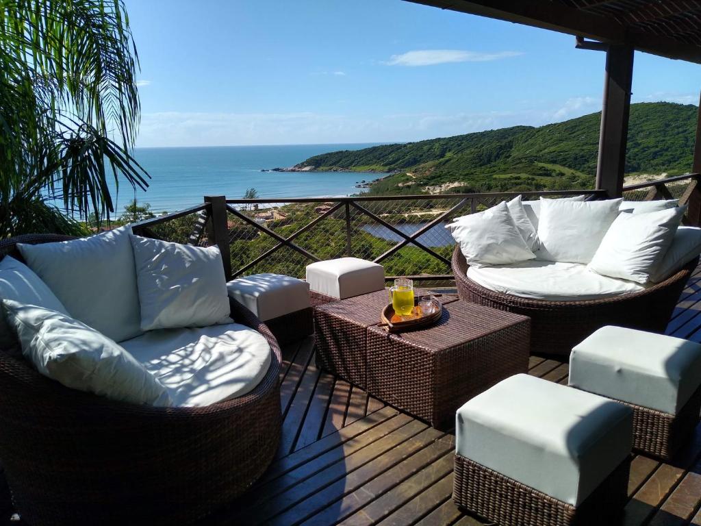 um deque com cadeiras e uma mesa com vista para o oceano em La Roca House na Praia do Rosa