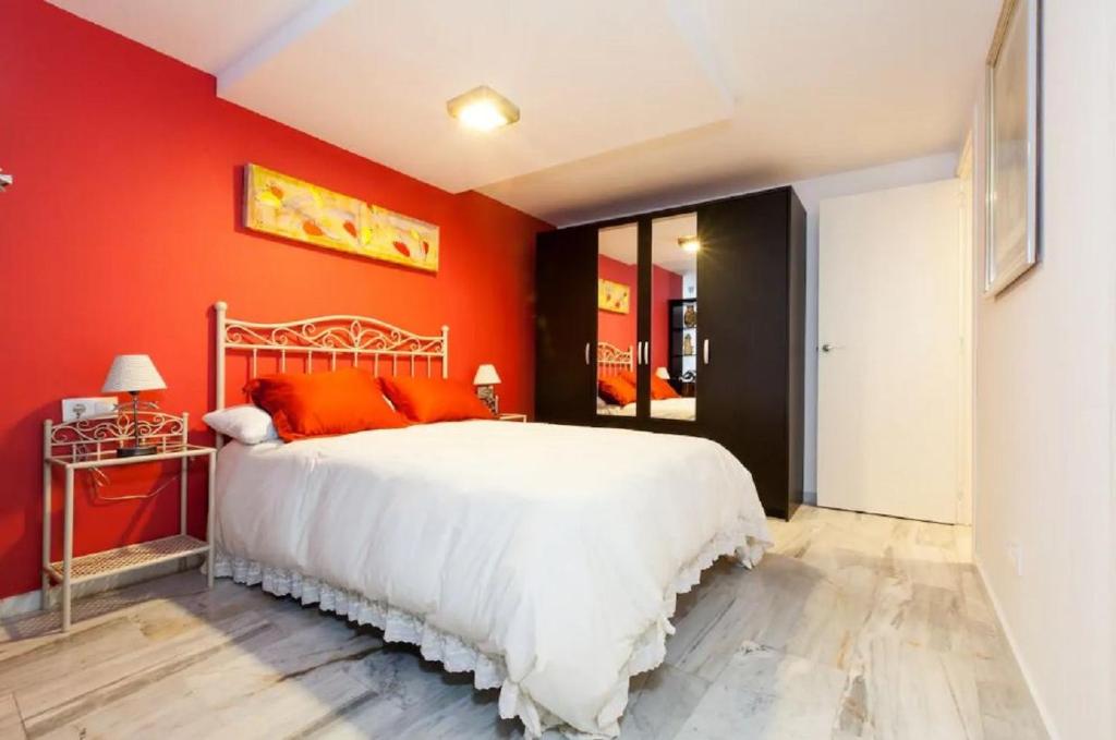 セビリアにあるApartamento Azaharの赤い壁のベッドルーム1室(白いベッド1台付)