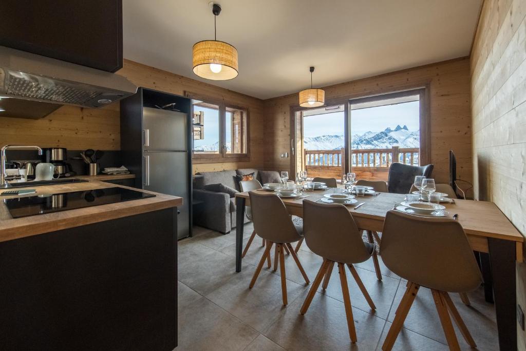 uma cozinha e sala de jantar com mesa e cadeiras em ODYSSEE CRC01 Appartement traversant sur les pistes em La Toussuire