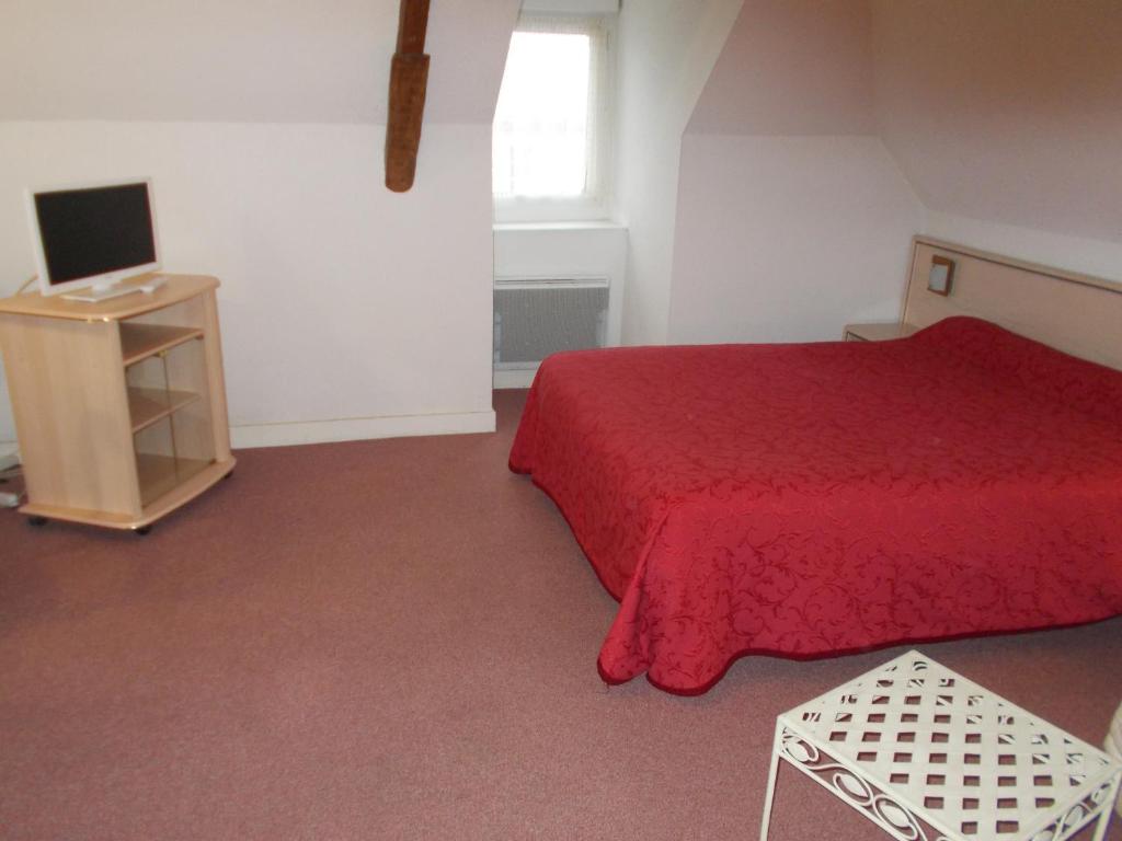 1 dormitorio con cama roja y TV en auberge de l arrivée, en Chemillé