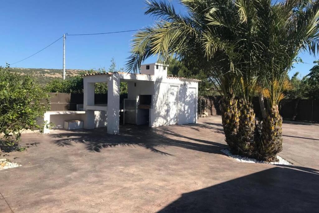 a white house with palm trees in front of it at TERRETA PISCINA Y PLAYA in Guardamar del Segura