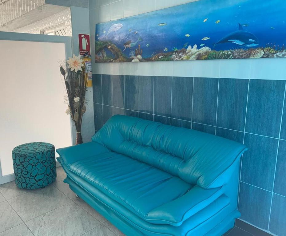 a blue couch in a room with a fish painting at Posada Cocos Place in San Andrés