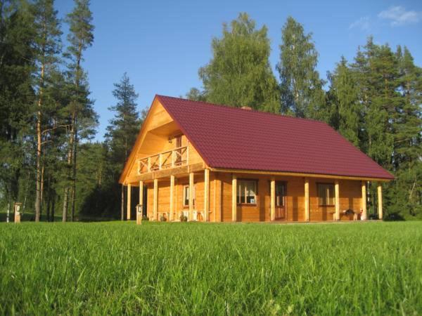 a large wooden house with a red roof in a field at Meldri in Vaidava