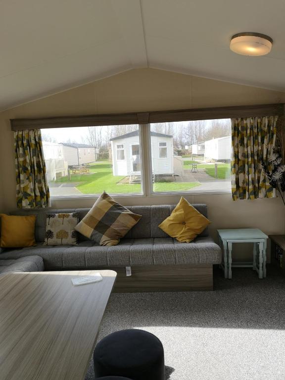 a living room with a couch and a large window at lakeland leisure park in Flookburgh