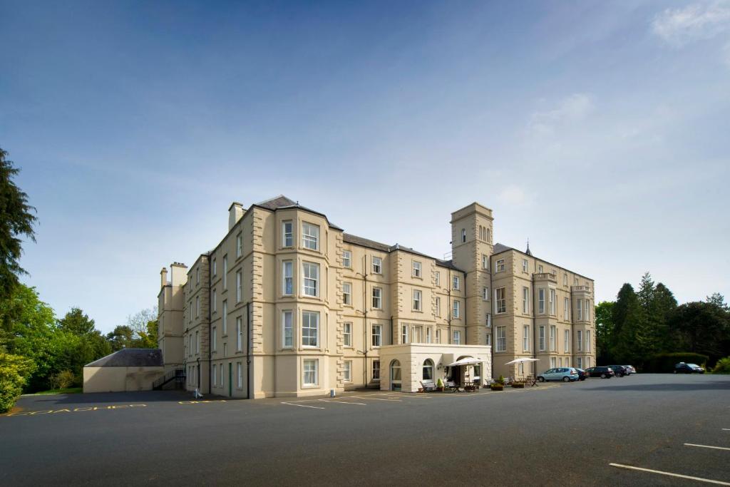 un grande edificio con auto parcheggiate in un parcheggio di The Waverley Castle Hotel a Melrose