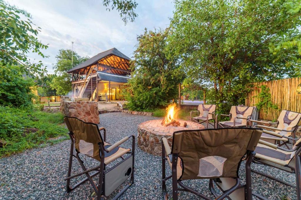 Lengau Lodge في Grietjie Game Reserve: حديقة خلفية بها كراسي ومدفأة وبيت