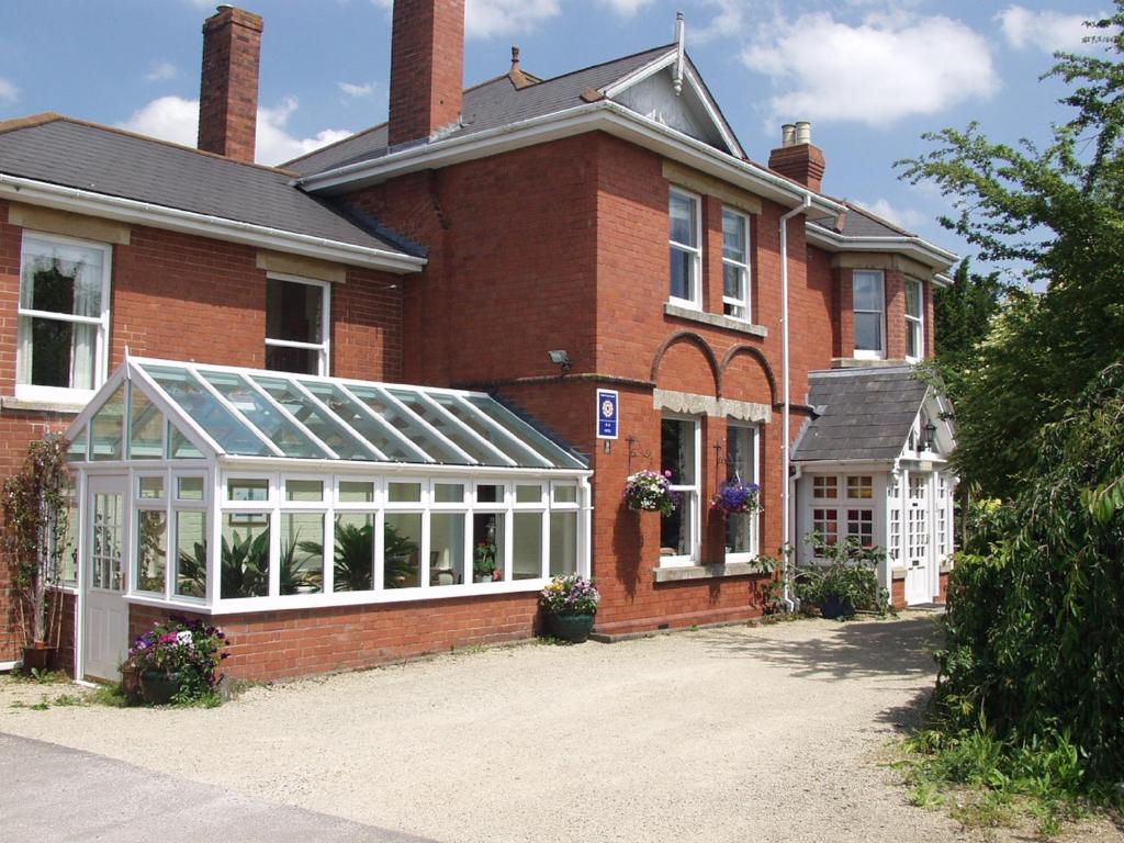 ein Backsteinhaus mit einem Gewächshaus davor in der Unterkunft Leadon House Hotel in Ledbury