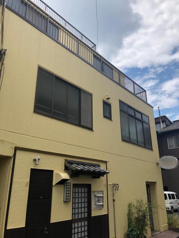 un edificio giallo con finestre nere sul lato di 尾道ゲストハウス シータ村 a Onomichi
