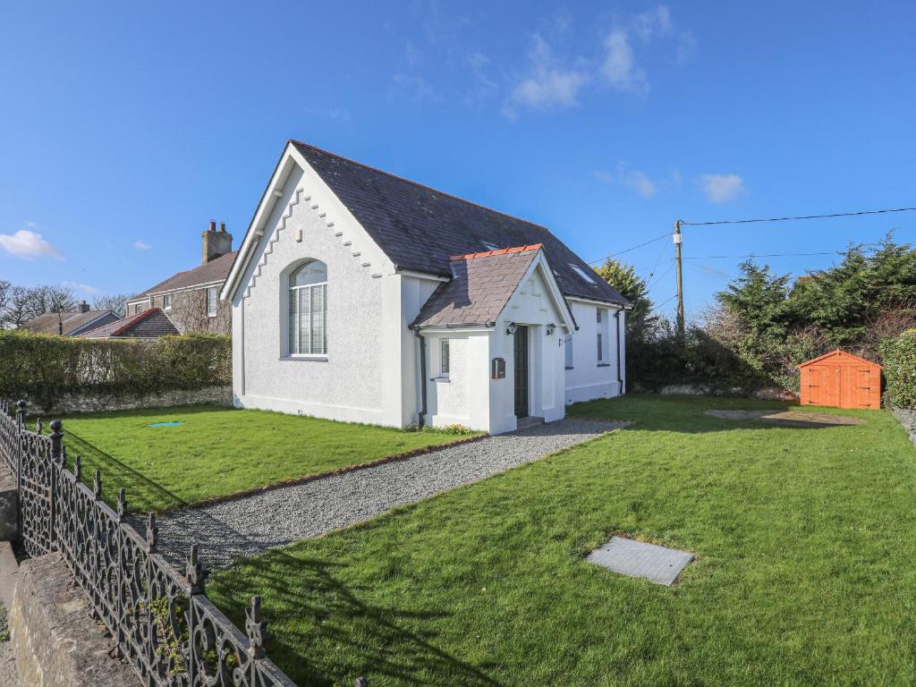 a small white building with a grass yard at Capel Hermon in Holyhead
