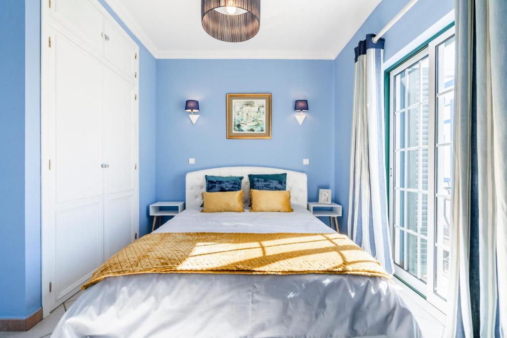 a blue bedroom with a bed and a window at Mouzinho Blueapartment in Cabanas de Tavira
