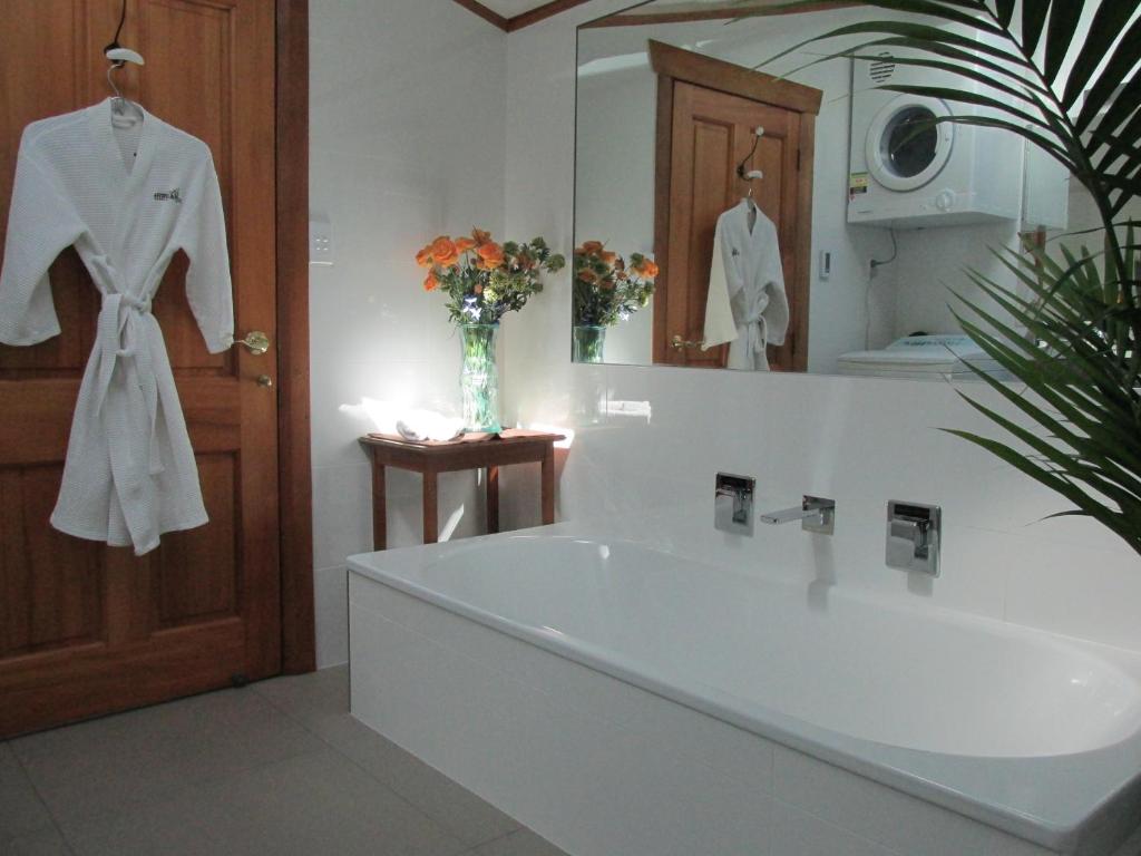 a bathroom with a large white tub and a mirror at Tarawhata Thermal Apartment in New Plymouth