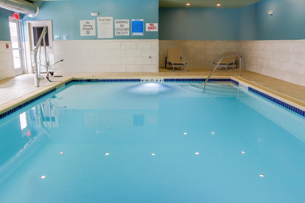 a swimming pool in a gym with blue water at Holiday Inn Express & Suites - Detroit Northwest - Livonia by IHG in Livonia