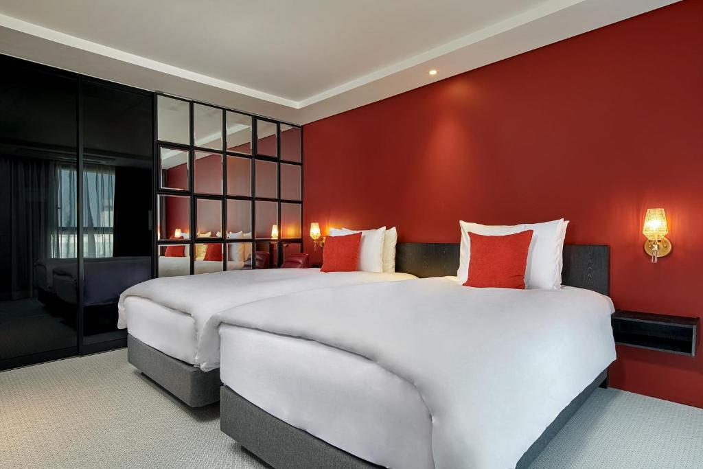 a bedroom with two beds and a red wall at Hotel Alice and Trunk in Jeju