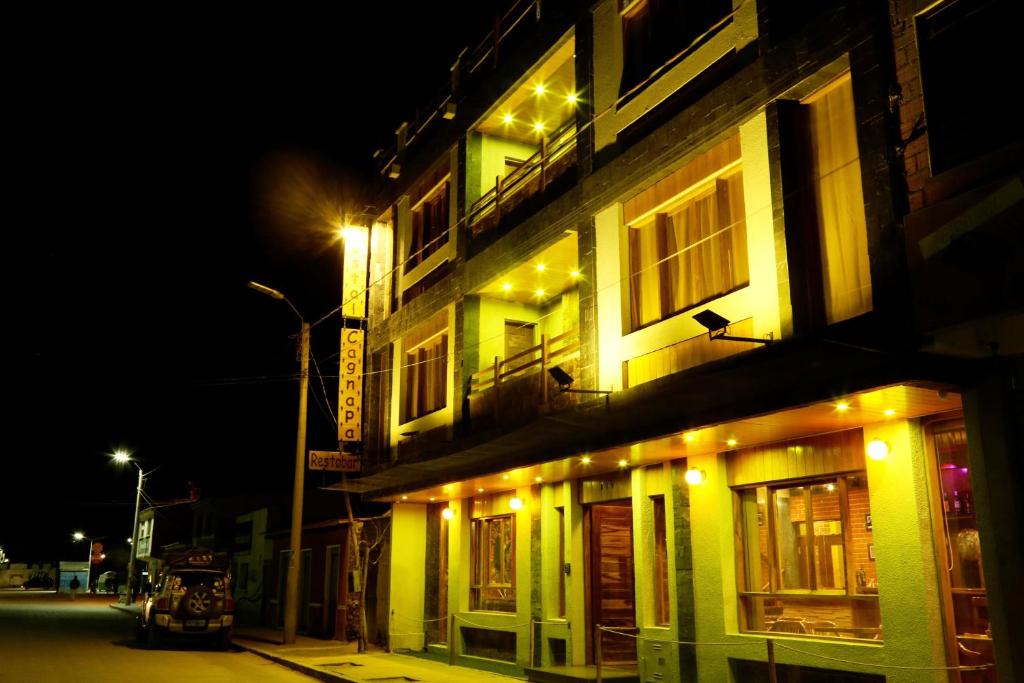 a lit up building on a street at night at Hostal Cagnapa Restobar in Uyuni